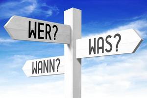wie, wat, wanneer vragen in Duitse - houten wegwijzer met drie pijlen en lucht in achtergrond foto