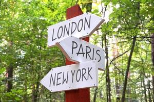 Londen, Parijs, nieuw york - houten wegwijzer met drie pijlen, Woud in achtergrond foto