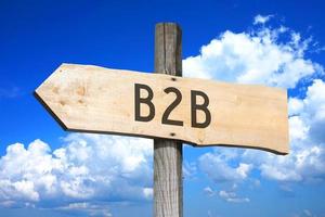 b2b, bedrijf naar bedrijf - houten wegwijzer met een pijl, lucht met wolken in achtergrond foto