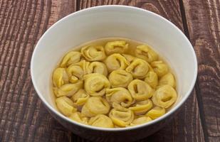 traditioneel Italiaans tortellini in brodo Aan houten tafel. foto