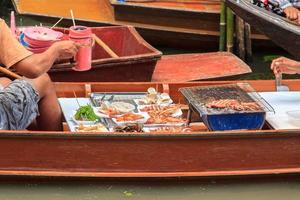 de boot dat verkoopt zeevruchten-bij damnoen saduak drijvend markt is een populair toerist bestemming dat Europeanen en Chinese mensen liefde naar reizen met traditioneel manieren van dorpelingen. foto