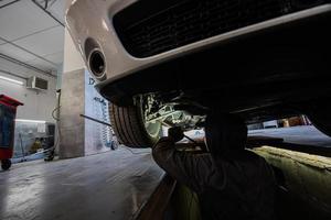 monteur in onderhoud reparatie station werken met spier auto. inspecteert de rennen een deel van de wiel. foto