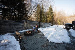 broer met zus zittend door kamp vreugdevuur Aan winter in Woud. kinderen in platteland. foto