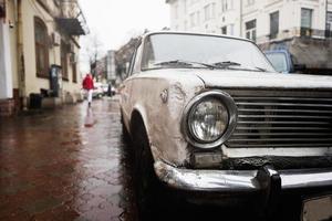 oud wijnoogst auto koplamp in regen stad straat. foto
