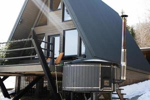 houten driehoek land klein cabine huis met heet kuip spa in bergen. ziel weekenden. foto