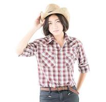 jong vrouw in een cowboy hoed en plaid overhemd met hand- Aan haar hoed foto