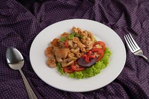 roeren garnaal macaroni Aan een wit bord met vork, lepel, tomaten en salade. foto