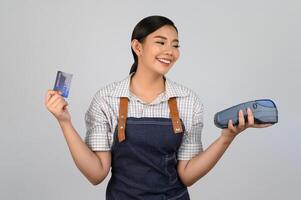 portret van jong Aziatisch vrouw in serveerster uniform houding met credit kaart foto