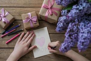 de jongen maakt een kaart voor moeder dag. materialen voor artistiek creativiteit Aan de kinderen tafel, kinderen tekeningen. foto