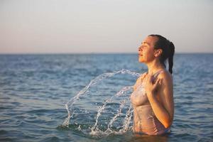 een middelbare leeftijd vrouw staat in de zee en spatten water. foto