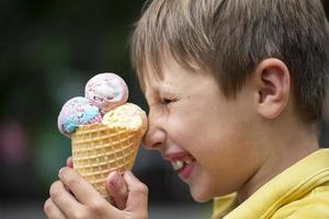 de jongen is klaar naar eten helder ijs room in een wafel ijshoorntje Aan een zomer dag. foto