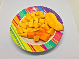 plakjes van mango en papaja fruit Aan een kleurrijk motief bord foto