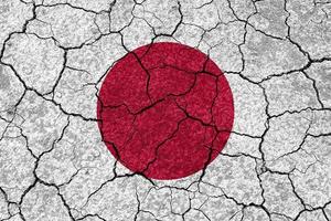aardbevingen in Japan, vlag Japan Aan een muur met scheuren van een aardbeving foto