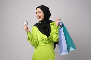 mooi moslim vrouw met hijab Holding credit kaart en boodschappen doen zak over- wit achtergrond studio, boodschappen doen en financiën concept. foto