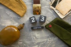 fles, pet, soldaat leger riem, oud foto's van de oorlog jaren en een houten kalender met de datum februari 23. foto
