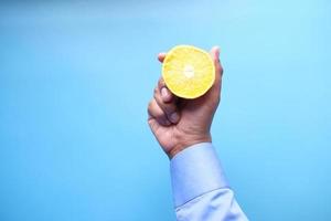 hand met citrusvruchten op blauwe achtergrond