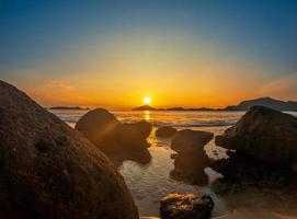 strand en rotsen in kust. mooi dramatisch oceaan zonsondergang foto