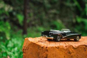 een foto van zwart speelgoed- auto Aan een steen in de tuin, na sommige bewerkingen.