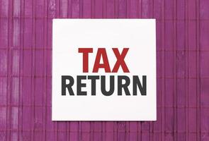 wit sticker met tekst belasting terugkeer Aan roze houten achtergrond foto