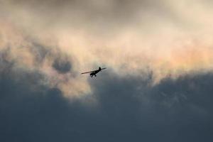 klein vlak vliegend in de lucht tegen donker wolken foto