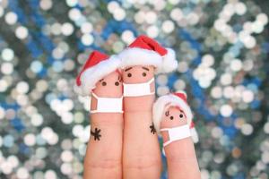 vingers kunst van familie in medisch masker van covid-2019 viert kerstmis. concept van mensen in nieuw jaar hoeden. foto