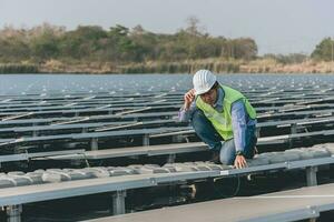 ingenieur inspecteur Holding laptop en werken in zonne- panelen macht fabriek controle fotovoltaïsche cellen en elektriciteit productie. foto