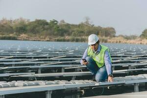 ingenieur inspecteur Holding laptop en werken in zonne- panelen macht fabriek controle fotovoltaïsche cellen en elektriciteit productie. foto