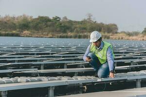 ingenieur inspecteur Holding laptop en werken in zonne- panelen macht fabriek controle fotovoltaïsche cellen en elektriciteit productie. foto