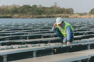 ingenieur inspecteur Holding laptop en werken in zonne- panelen macht fabriek controle fotovoltaïsche cellen en elektriciteit productie. foto