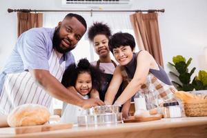 gelukkig Afrikaanse Amerikaans familie genieten samen terwijl bereiden de meel voor maken koekjes Bij huis foto