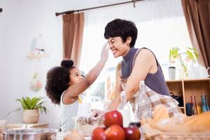 gelukkig Afrikaanse Amerikaans familie genieten samen terwijl bereiden de meel voor maken koekjes Bij huis foto