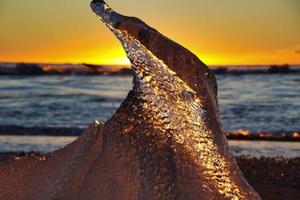 ijs Aan de strand Bij zonsopkomst foto