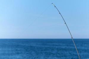 visvangst hengel tegen blauw oceaan of zee achtergrond, kopiëren ruimte. aan het wachten voor grootste lading. meditatief kom tot rust sport. foto