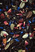 zwart los blad thee structuur met droog fruit, kruiden en bloem bloemblaadjes foto