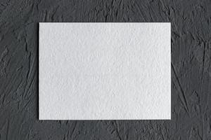 wit getextureerde papier kaart Aan donker beton achtergrond foto