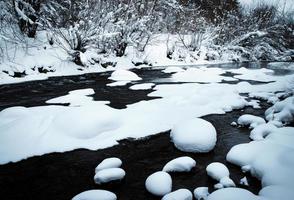 winter rivier met dekens van verse sneeuw foto