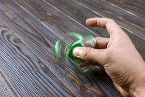 jongen hand- spelen met friemelen spinner apparaatje. groen hand- spinner, friemelen hand- speelgoed- roterend Aan Mens hand- foto