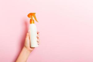 vrouw hand- Holding verstuiven room fles van lotion geïsoleerd. meisje geven kunstmatig producten Aan roze achtergrond foto