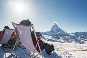 jong snowboarder juichen met een bier na skiën dag in een bar of een cafe Bij de zermatt ski toevlucht in Zwitsers Alpen met een fantastisch visie van de materiehoorn. winter vakantie concept. foto