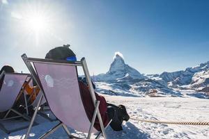 jong snowboarder juichen met een bier na skiën dag in een bar of een cafe Bij de zermatt ski toevlucht in Zwitsers Alpen met een fantastisch visie van de materiehoorn. winter vakantie concept. foto