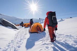 groep van berg klimmers beklimmen de helling naar de top in zonnig weer met sleeën en tenten uitrusting voor 's nachts blijft foto