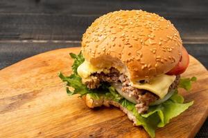 vers eigengemaakt hamburgers, heerlijk vers groenten, sla, tomaten, kaas dat zijn gebeten Aan een snijdend bord, vrij ruimte voor berichten foto