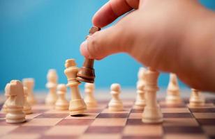 de hand- van zakenman Holding bruin koning schaak en schaakmat concurrent en winnen de spellen. concept van leiderschap moet hebben een bedrijf strategie en concurrent evaluatie in wedstrijd foto