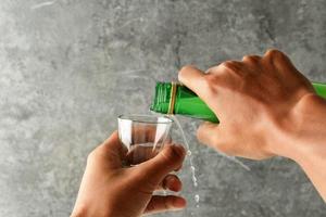 mand hand- gieten soju Koreaans alcohol naar de sloki glas, foto