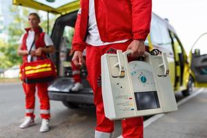 hand- van de dokter met defibrillator. teams van de noodgeval medisch onderhoud zijn reageren naar een verkeer ongeluk. foto