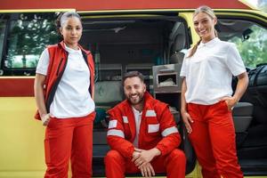 Vrolijk, glimlachen artsen werken team staand door de ambulance. foto