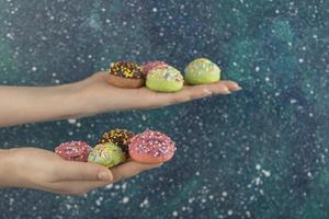 handen met kleurrijke zoete kleine donuts met hagelslag