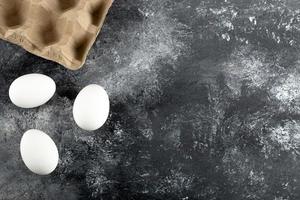 drie rauwe kippen verse eieren op een marmeren achtergrond foto