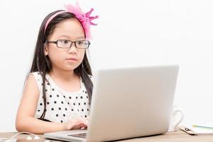 schattig meisje Speel computer Aan wit achtergrond foto