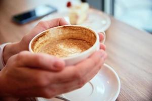 vrouw hebben ontbijt Bij cafe, houden koffie pet in handen foto